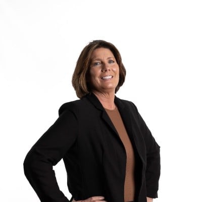 Professional headshot of a woman in a black blazer smiling against a white background